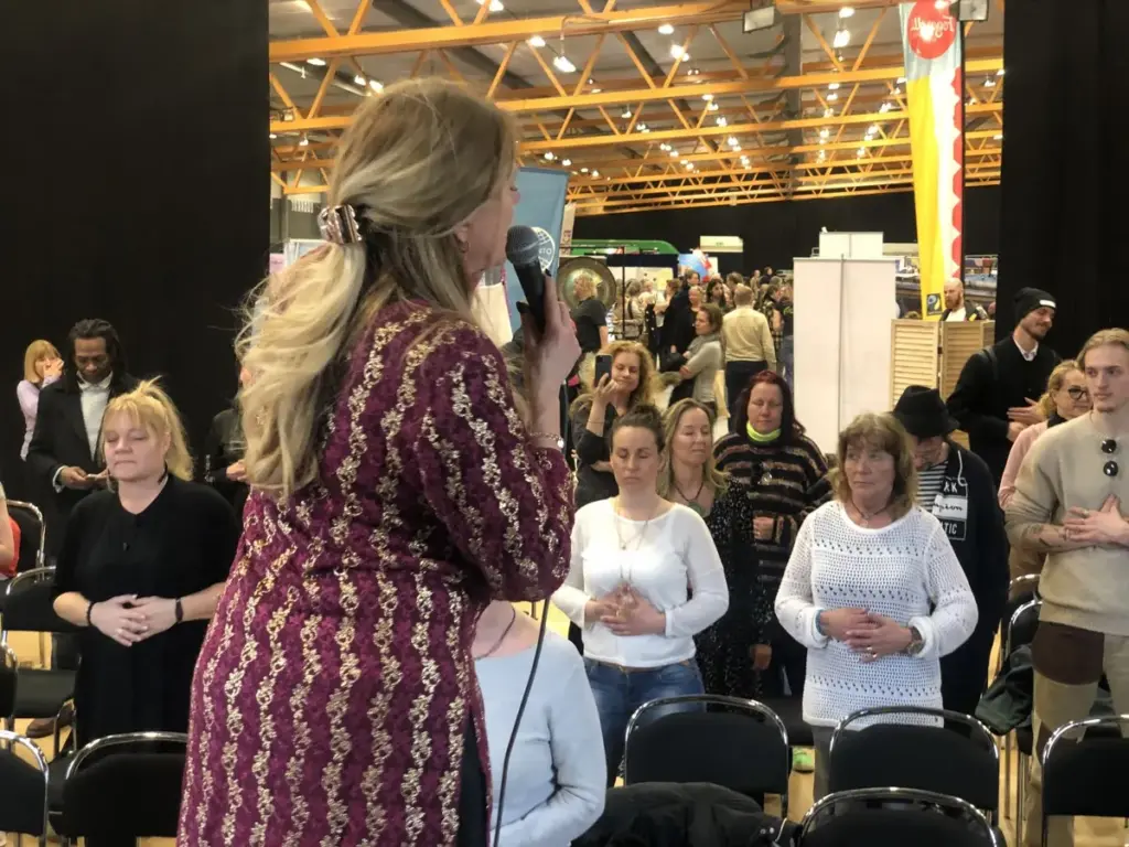 Besökare står med händerna på hjärtat och blundar under ett pass på mässan