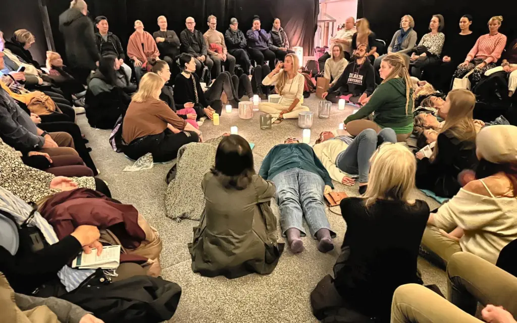 Besökare sitter och ligger i en ring runt passledaren på Hyllan